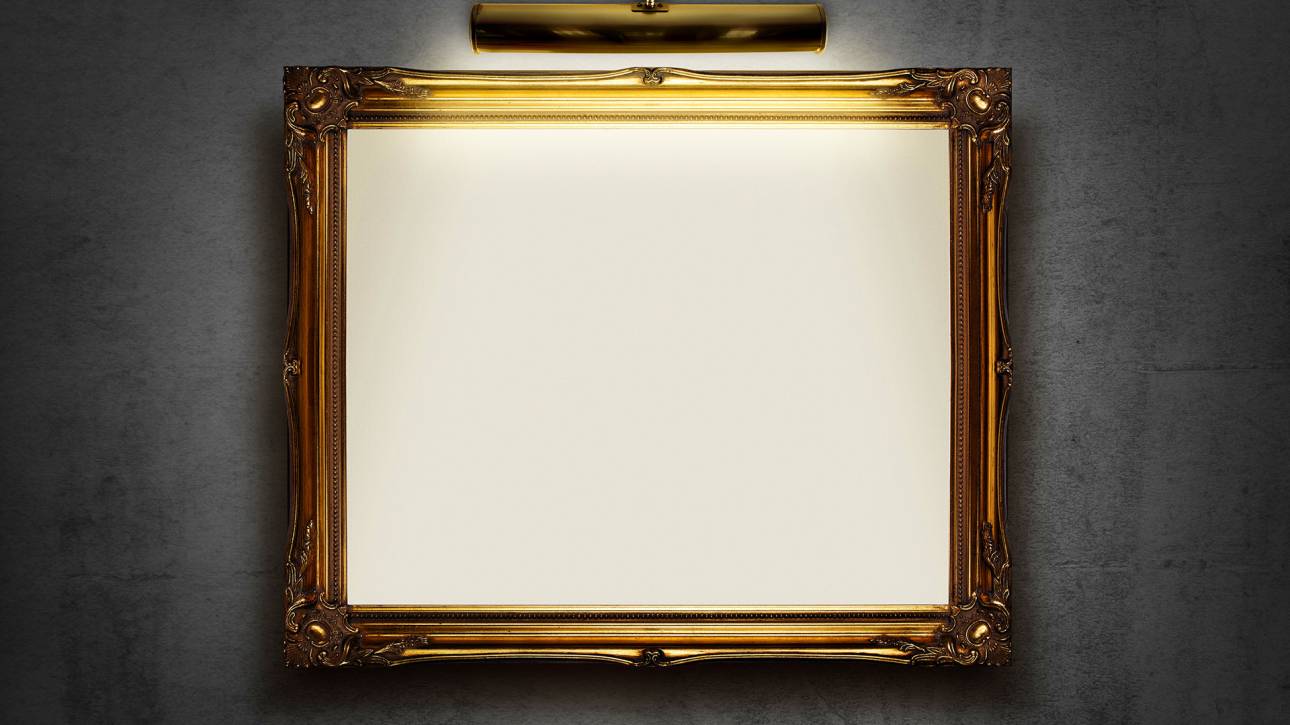 Ornate gold picture frame with spotlight on dark wall