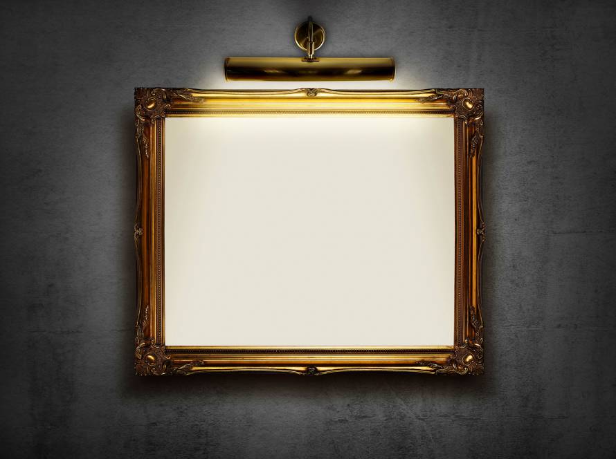 Ornate gold picture frame with spotlight on dark wall