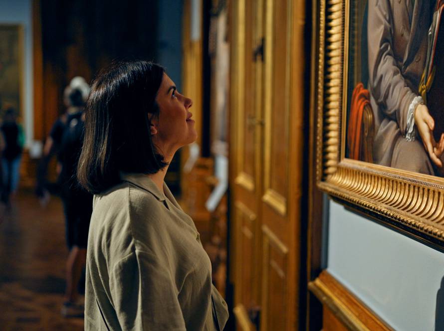 Woman looking at a framed painting on display in an art gallery